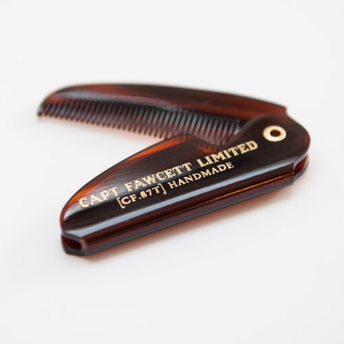 A brown wooden comb with gold-colored text for Capt. Fawcett Limited on it.