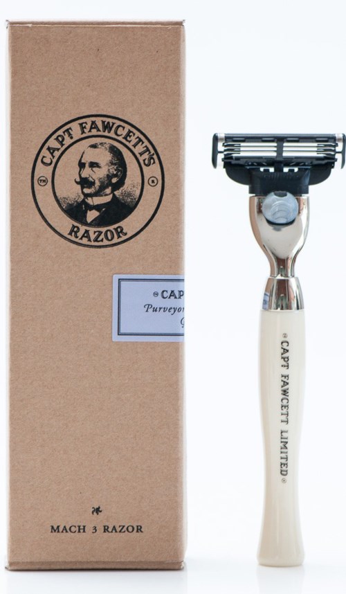 A vintage-style razor with a white handle and a black razor blade head next to a brown box with a logo.