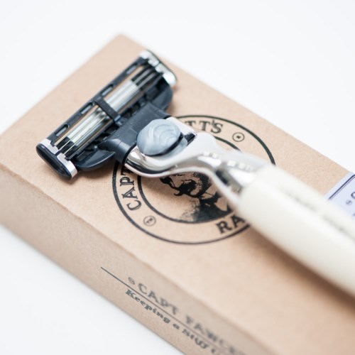 A razor is placed on a cardboard box, with a small amount of white shaving cream on the razor.