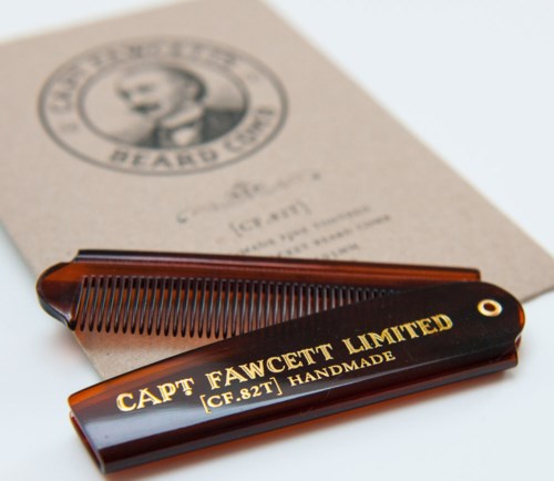 A brown hair comb and a small label with gold text reading "CAPT FAWCETT LIMITED" are on white paper.