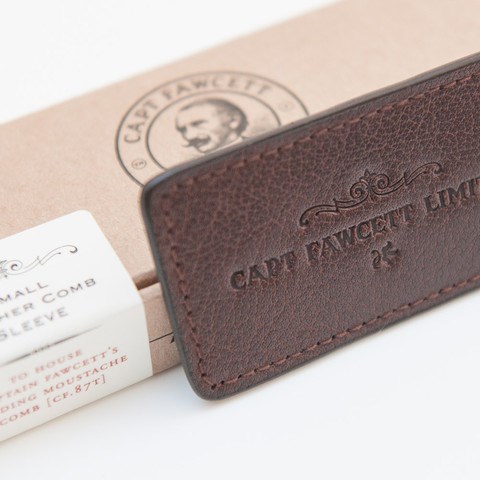 A dark brown leather wallet with embossed text, placed on a light-colored box with a logo of a man's face.