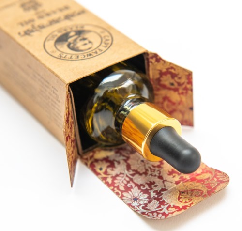 A small glass bottle with a black dropper cap inside a partly opened decorative cardboard box.