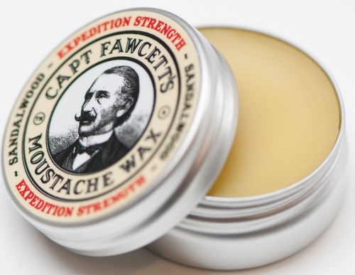 A small round tin of moustache wax with a label showing a man and the product name.