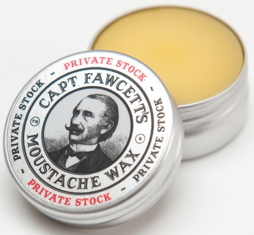 A tin container of moustache wax with a picture of a man and text on the lid.
