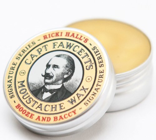 A small round container of mustache wax with a vintage-style label featuring a man's face and text.
