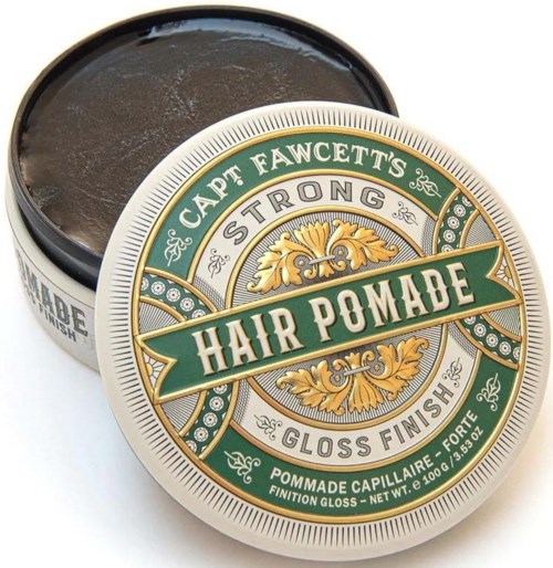 A tin of hair pomade with a decorative标签, green, gold, and white design, opened to show dark product inside.