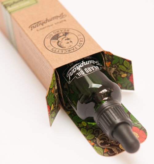 A dropper bottle is inside a decorative box, with the dropper sticking out, surrounded by colorful floral patterns.