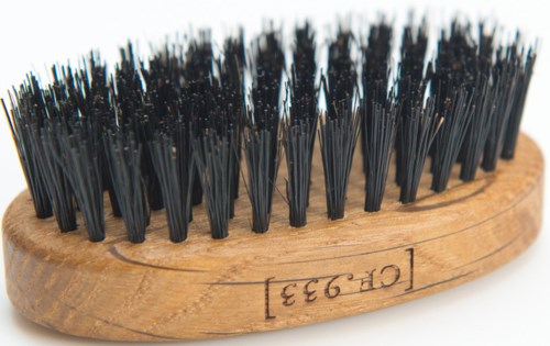 En träskosborste med svarta piggar, oval form och ett modellnummer på sidan.
