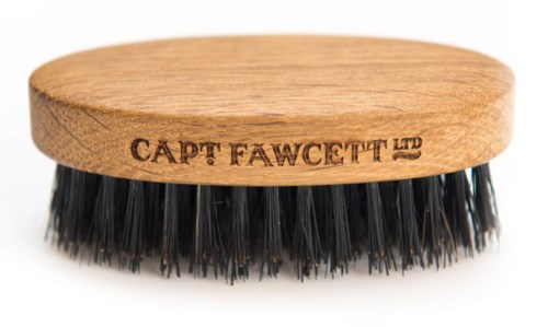 En liten trebørste med svarte børster og teksten 'CAPT FAWCETT LTD' inngravert i treet.