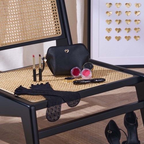 Make-up-spullen, zwarte tas, handschoenen en schoenen op een stoel, met hartpatroon op de achtergrond.