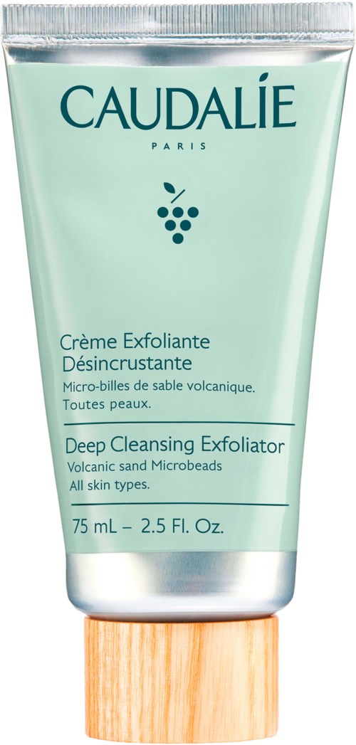 A facial scrub tube with a wooden cap, light green label, and text about deep cleansing for all skin types.