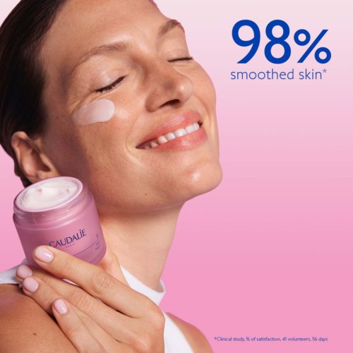 Hymyllä oleva nainen, joka pitää kädessään pinkkiä ihonhoitorasiaa, mainostaa 98 % tasaisempaa ihoa.