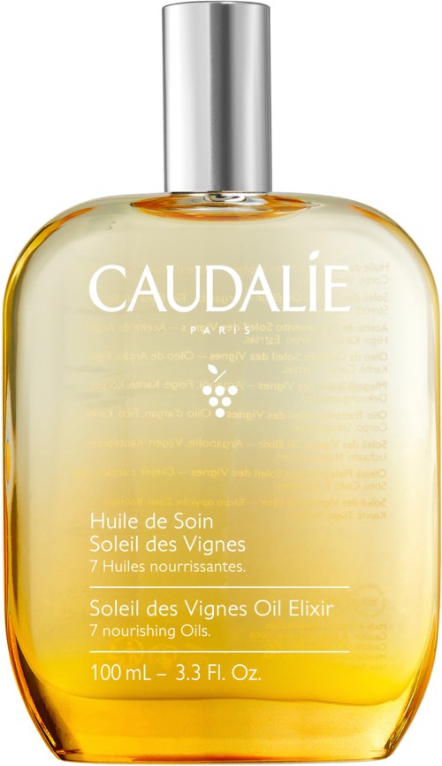 Caudalie Paris öljyeliksiiri kirkkaassa pullossa, keltainen neste, hopeinen korkki, merke ja tiedot etikettissä.