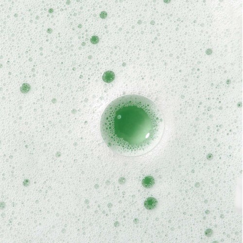 A green liquid bubbles in a white foam, with many small and a few large bubbles floating around.
