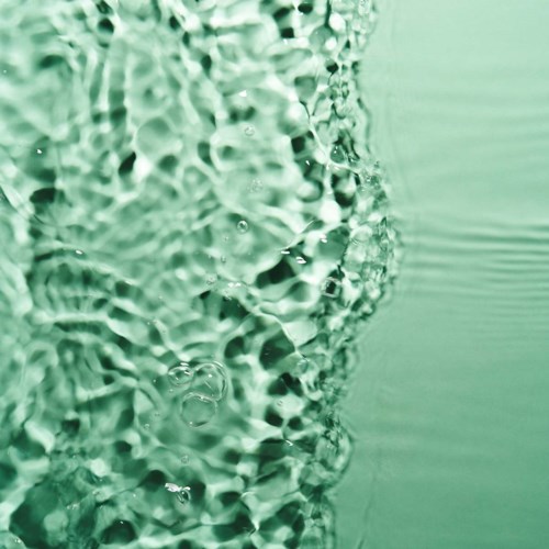 Bubbles rise from a surface under water with a green tint, creating ripples and foam.