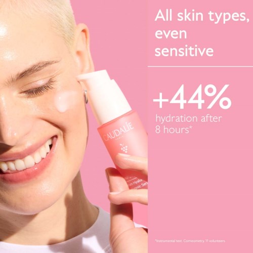A smiling woman with fair skin uses a skincare product, highlighting benefits for sensitive skin and hydration.