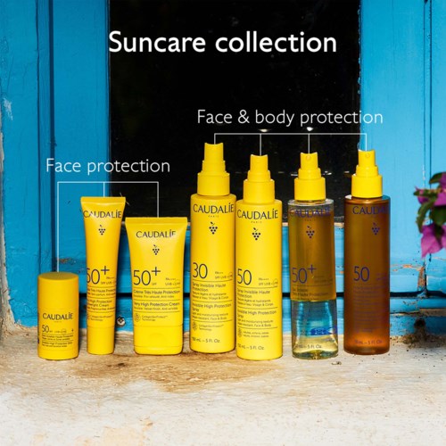 A collection of yellow bottles and tubes labeled for sun protection and skincare, arranged outdoors.