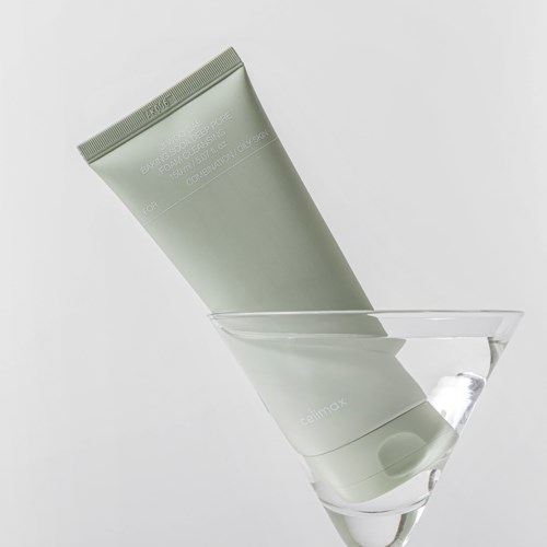 Ein hellgrüner Tube, teilweise in ein klares Martini-Glas mit Wasser eingetaucht.