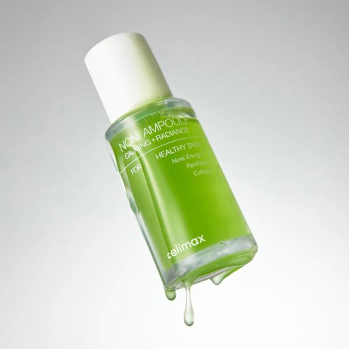 Eine grüne Hautpflegeflasche mit weißem Deckel, Tropfen Flüssigkeit und Text über gesunde Haut.