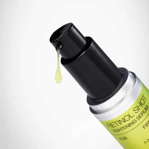 Kleine Flasche mit schwarzem Verschluss und gelbem Etikett, Tropfen Serums.