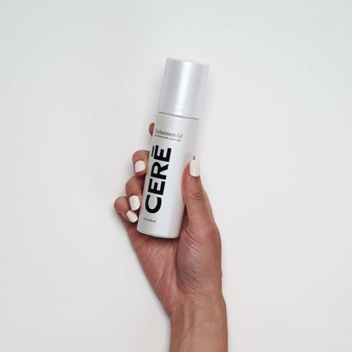A hand holds a white spray can labeled 'CERE' against a white background.
