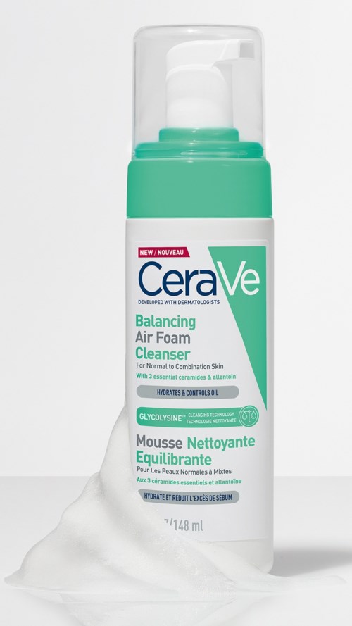A white and green bottle of CeraVe Balancing Air Foam Cleanser with some foam spilling out.