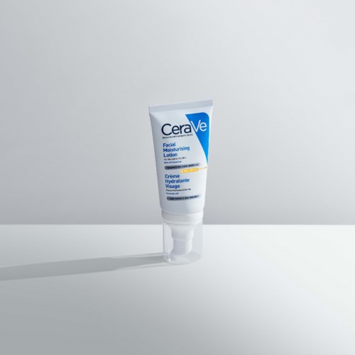 A white tube of CeraVe facial moisturizer stands on a surface, casting a shadow against a plain background.