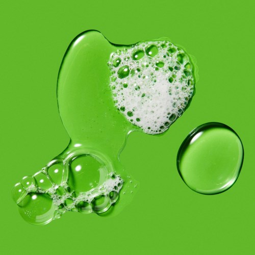 A green liquid with bubbles and a round droplet on a green background.