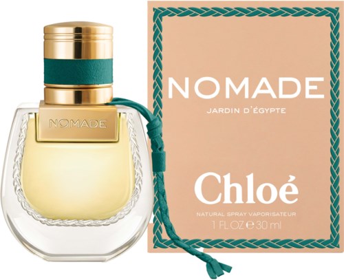 Een parfumfles met 'NOMADE' naast een roze doos met witte tekst en blauwe koord, voor Chloé.
