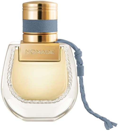 Een doorzichtige parfumfles met gouden en blauwe details, een gevlochten touw en het woord 'NOMADE'.