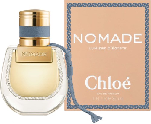 Een parfumfles met label 'NOMADE' en bijpassend doos met roze achtergrond en blauwe rand.