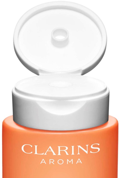 Een koraalkleurige pot met een open wit deksel, gemerkt 'Clarins Aroma', waarschijnlijk voor huidverzorging of cosmetica.