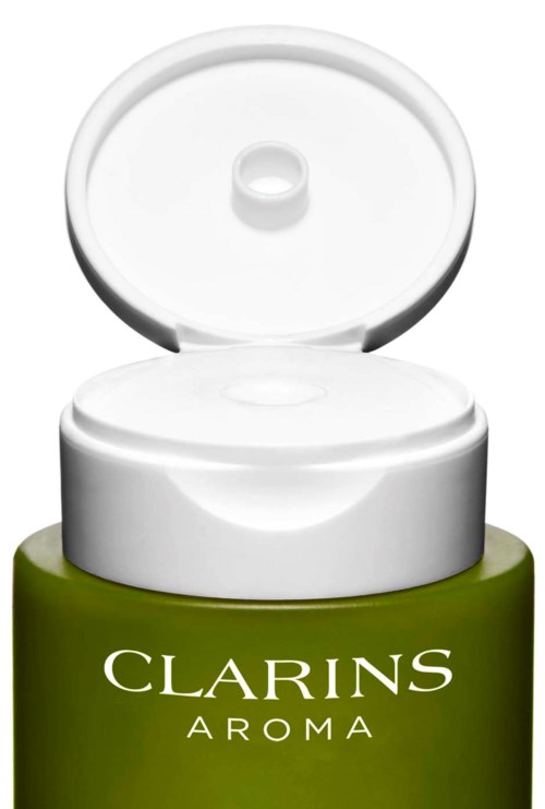 Een kleine groene container met een wit dekseldop, gemarkeerd 'CLARINS AROMA'.