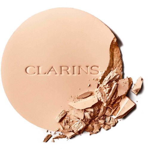 A beige pressed powder with the Clarins logo, partly broken with fragments around it.