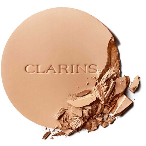 A beige pressed powder with the brand name "CLARINS" and some broken pieces around it.