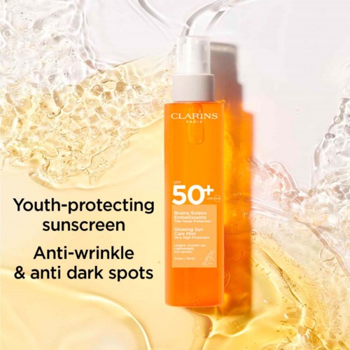Clarins Sonnencreme mit SPF 50+ umgeben von goldener und klarer Flüssigkeit.