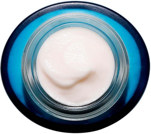 A small jar of white cream or lotion seen from above, on a blue lid or surface.