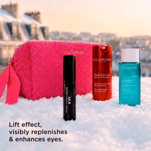Clarins skincare products on snow with a pink towel, promoting eye enhancement and replenishing effects.