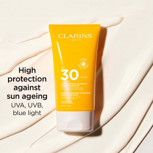 Een gele zonnebrandcrème tube met SPF 30, met witte en zwarte tekst, op een crèmekleurige achtergrond.