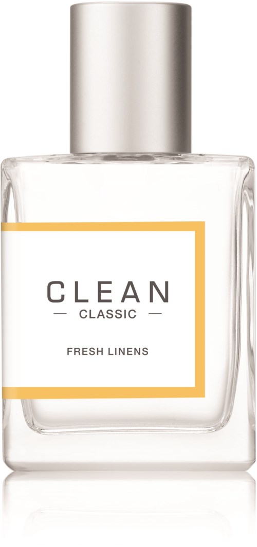 Een doorzichtige parfumfles met label 'CLEAN CLASSIC FRESH LINENS' en zilveren dop.