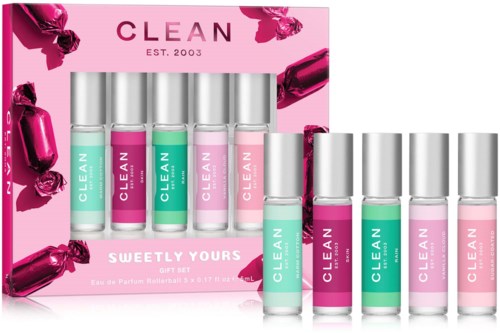 Box with six small bottles of perfume in pastel pink and green, labeled CLEAN, with a pink background and candy wrappers.