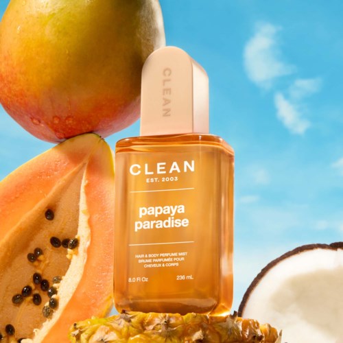 Eine Flasche Papaya-Duftparfüm mit Papaya und Kokosnuss in der Nähe unter blauem Himmel.