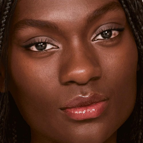 Een close-up van een vrouw met een gladde huid, glanzende lippen en donker gevlochten haar.