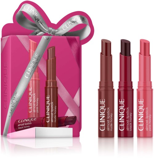 Three Clinique lipsticks in shades of brown and pink with a pink gift box and silver ribbon.