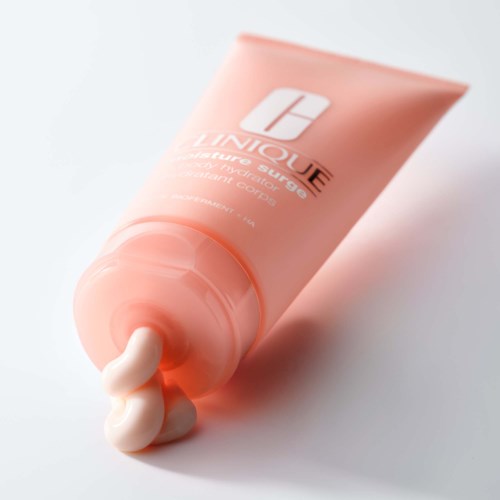Een roze tube met klikdop, gelabeld 'LINIQUE' en 'Smoothing Supplement', met crème die eruit komt.