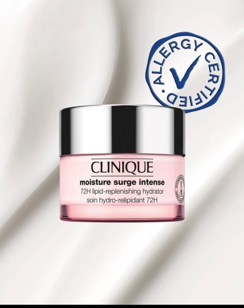 A pink jar of Clinique moisturizer with a black and silver lid, placed on a silky white fabric. An allergy-certified seal is visible.
