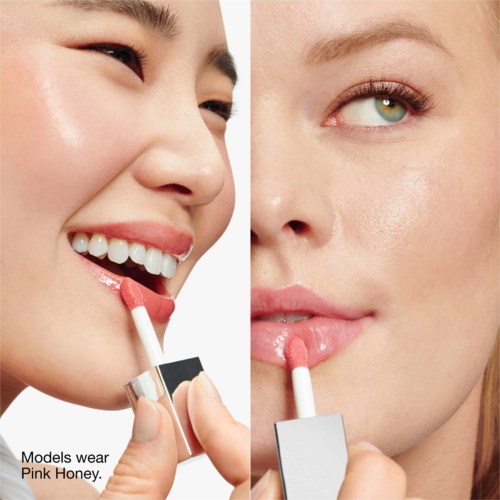 Zwei Frauen tragen pinken Lippenstift auf, Nahaufnahme von Gesichtsmerkmalen und glatter Haut, eine lächelt, die andere schaut ruhig.