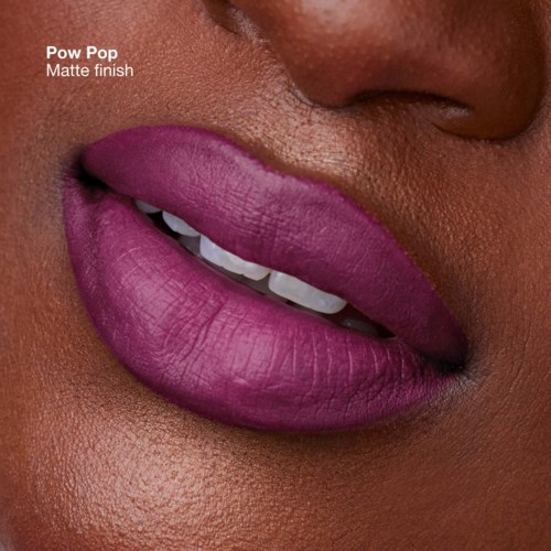 Close-up van donkere lippen met matte paarse lipstick, licht geopend met witte tanden zichtbaar.