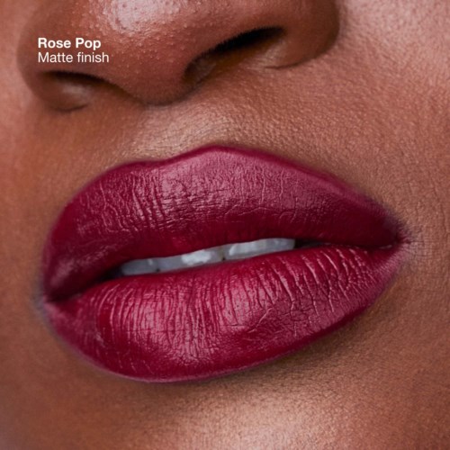 Close-up of lips with matte rose-colored lipstick, slightly parted showing teeth.