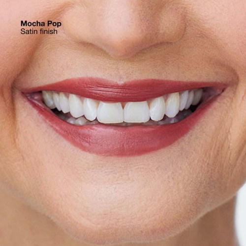 Close-up of a smiling mouth with white teeth and pink lipstick. Text indicates lipstick shade is Mocha Pop, satin finish.